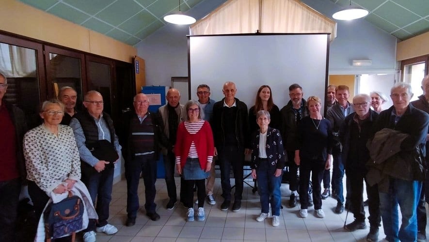 Une vingtaine de membres de l'association réunis debout dans une salle, devant un écran de projection
